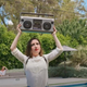 Zoe Lister-Jones holds up a boom box, Say Anything-style, in a scene from How It Ends.